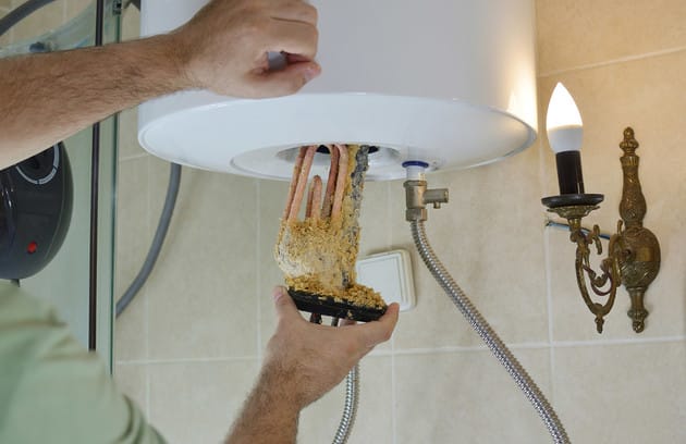 Technician removing mineral buildup from a water heater in Alpharetta